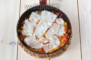 Филе хека выньте из маринада, нарежьте и выложите на подушку из овощей. Лёгким нажатием немного «утопите» рыбу. Если на филе остались кусочки чеснока, не убирайте их. Добавьте 2 ст. л. маринада.