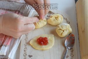Каждый кусочек теста немного раскатываем скалкой или приплюснем рукой, чтоб был такой кружок. Кладём на него 0,5 чайной ложки конфитюра и залепливаем, формируя типа шарик. Кусочки теста, с которыми пока не работаем, накроем полотенцем, чтоб не обветривалось.
