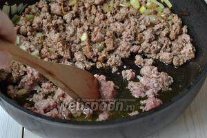 Добавьте к луку фарш. Кладите небольшими кусочками и измельчайте, разрезая крупные комочки лопаткой, пока мясо не успело схватиться. В противном случае получится большая котлета, которую сложно будет разделить на мелкие части.