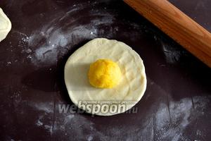 Каждый кусочек теста раскатать в небольшую лепёшку. Из начинки сформировать шарики в количестве, равном количеству кусочков из теста. Шарик из начинки положить в центр лепёшки из теста.