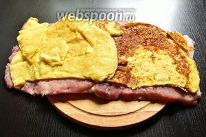 Яичные блинчики выложить на отбитый кусок свинины, так, чтобы он покрыл практически весь кусок. 1 край оставляю свободным на 1-2 см от блина.