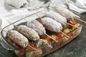 Поверх картофеля в соусе укладываем шпажки с кебабами. Отправляем блюдо в горячий духовой шкаф.