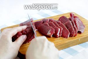 Слегка подмороженную мякоть нарезать тонкими пластинками, а затем поперёк тонкой соломкой. Чем тоньше нарезка, тем быстрее мясо приготовится.