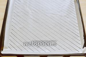 Вначале подготовим бумагу для выпечки диагонального цветного бисквита. Нарисуем на бумаге диагональные полоски шириной 1 см, перевернув бумагу. Положим её на противень. Противень у меня размером 30х35 см. Включим духовку на 180°С и займёмся тестом.