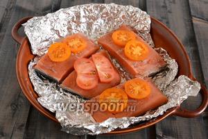 Разрежьте рыбное филе на порционные кусочки и выложите на фольгу. Можно обойтись и простой формой, но, как опытным путём выяснилось, к фольге крошки совершенно не прилипают, поэтому такой способ просто удобнее.
На рыбу выложите тонкие ломтики помидоров, посолите и поперчите.
