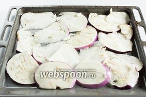 Шайбы баклажанов смазываем руками, увлажнёнными растительным маслом, укладываем их на противни (получится почти что 2) и держим в духовке на температуре 200°С 20 минут.