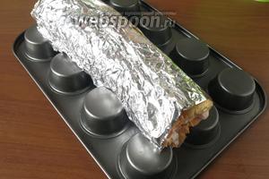 Кладём рулет между формами для маффинов, чуть вдавливая стороной, противоположной месту соединения роллов. Охлаждаем 2 часа в морозильнике или ночь в холодильнике. Готовила и так, и так, больше понравилось длительное охлаждение при более высокой температуре. Можно закрепить рулет к форме плёнкой.