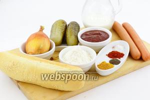 Для приготовления возьмите такие продукты: булочки для хот-догов, сосиски венские, кетчуп, горчицу, солёные огурцы, лук репчатый, муку, куркуму, паприку молотую, соль, чёрный перец, молотый чеснок, масло подсолнечное.