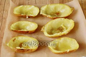 Половинки картофеля, с помощью силиконовой кисточки, смазать изнутри небольшим количеством масла (20 мл), каждую приправить солью и чёрным молотым перцем по вкусу, затем переложить на противень, застеленный пекарской бумагой, и вернуть в духовку ещё на 7-10 минут, чтобы они запеклись практически до хруста.