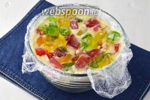 Глубокую куполообразную форму выложить пищевой плёнкой. Вылить в неё сметану и всыпать вперемешку нарезанные разноцветные кубики из желе. Накрыть сверху плёнкой и отправить в холодильникна 3-4 часа.