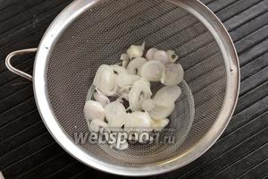 1/2 часть луковицы очистить, нарезать тонкими полукольцами, выложить на дуршлаг и окунуть в кипяток на 5 секунд. Дать стечь воде.