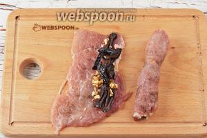 На один край (длинный) каждого промаринованного куска мяса выкладывать немного чернослива и грецких орехов. Завернуть каждый кусок рулетиком и выложить швом вниз.