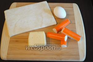 Подготовить небольшой набор продуктов: крабовые палочки, слоёное тесто, сыр твёрдых сортов, желток для смазывания теста.