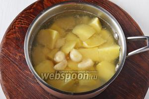 Поместить картофель и очищенный чеснок (1 головку) в кипящую подсоленную воду. Довести до кипения и варить 6-7 минут (до полуготовности).