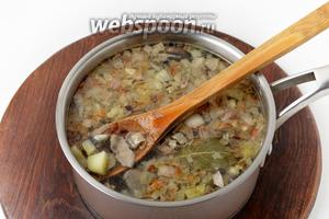 Выложить содержимое сковороды, 2 лавровых листика, перцы горошком (3 чёрного и 2 душистого) и грибной отвар в кастрюлю с картофелем. Довести до кипения и готовить 1-2 минуты.